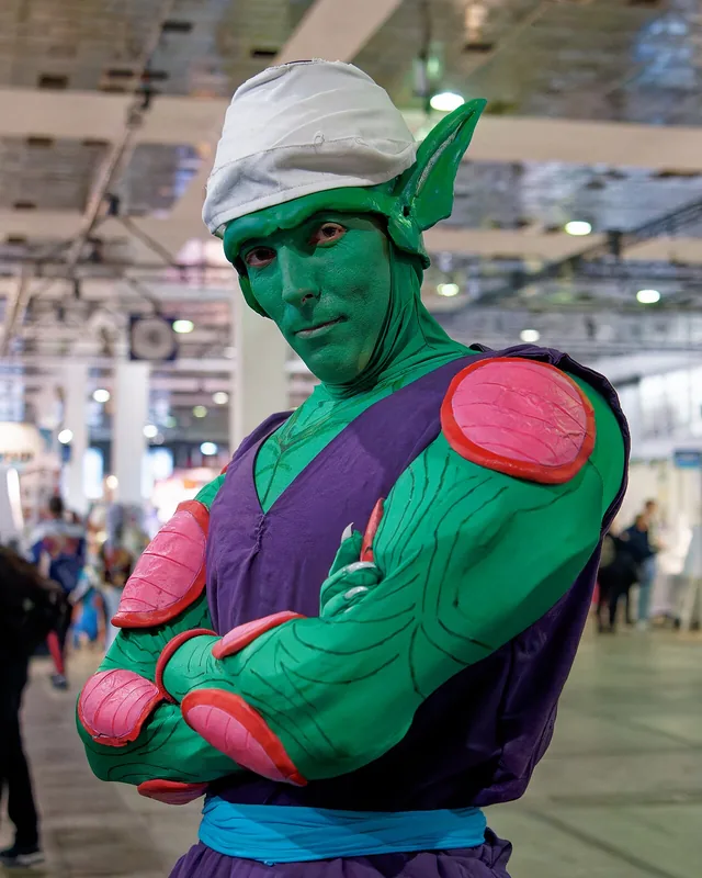 Cosplayer de Piccolo, bras croisés et demi-sourire, dans une convention