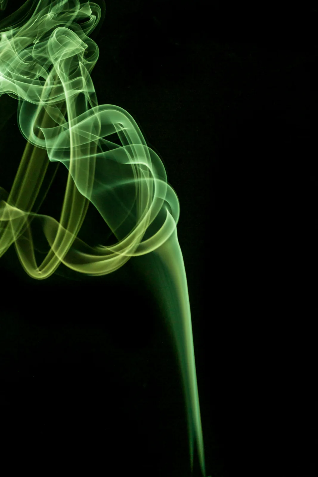 Espiral de fumaça verde iluminada sobre fundo preto, representando a aura verde